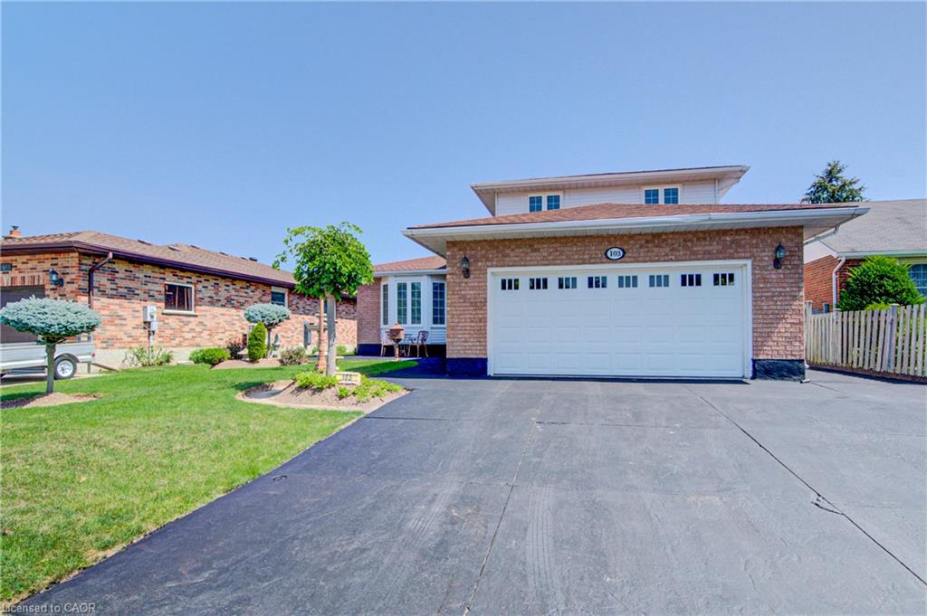 Brick exterior with a white garage door, a prominent front lawn, and a paved driveway