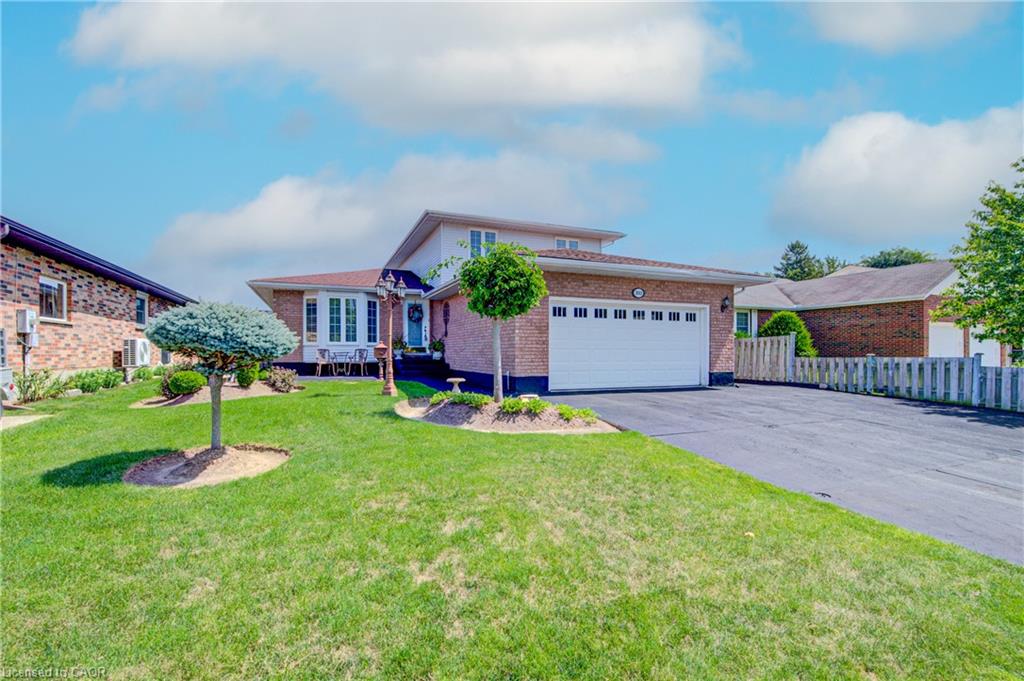 Brick facade with a white garage door, asphalt driveway, and a manicured lawn