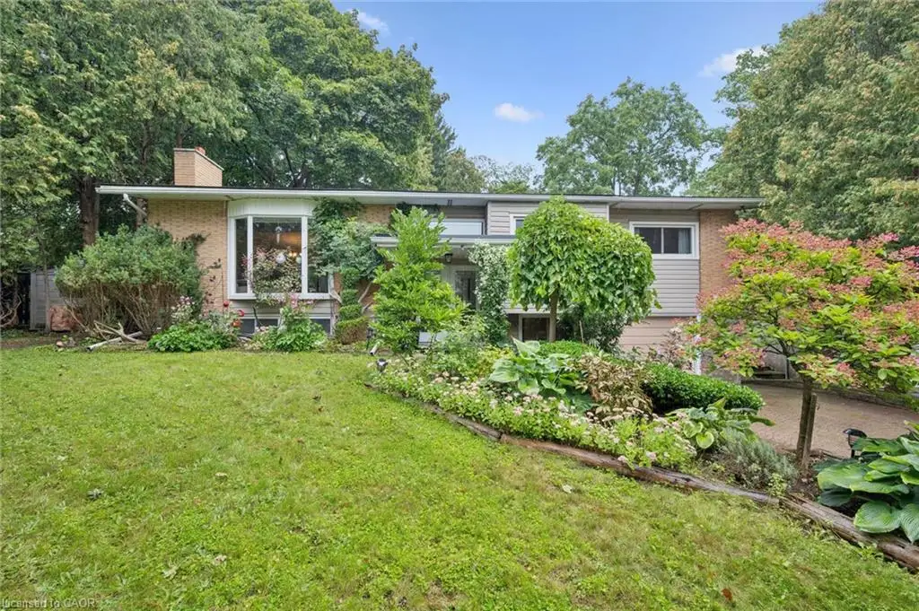 Brick and siding exterior with a prominent bay window, mature landscaping, and a well-maintained lawn