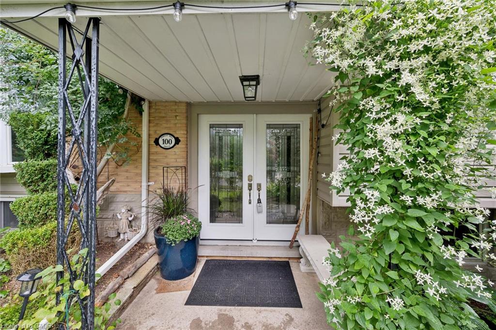 Double entry doors with decorative glass panels, brick exterior, overhead lighting fixture, and a covered porch