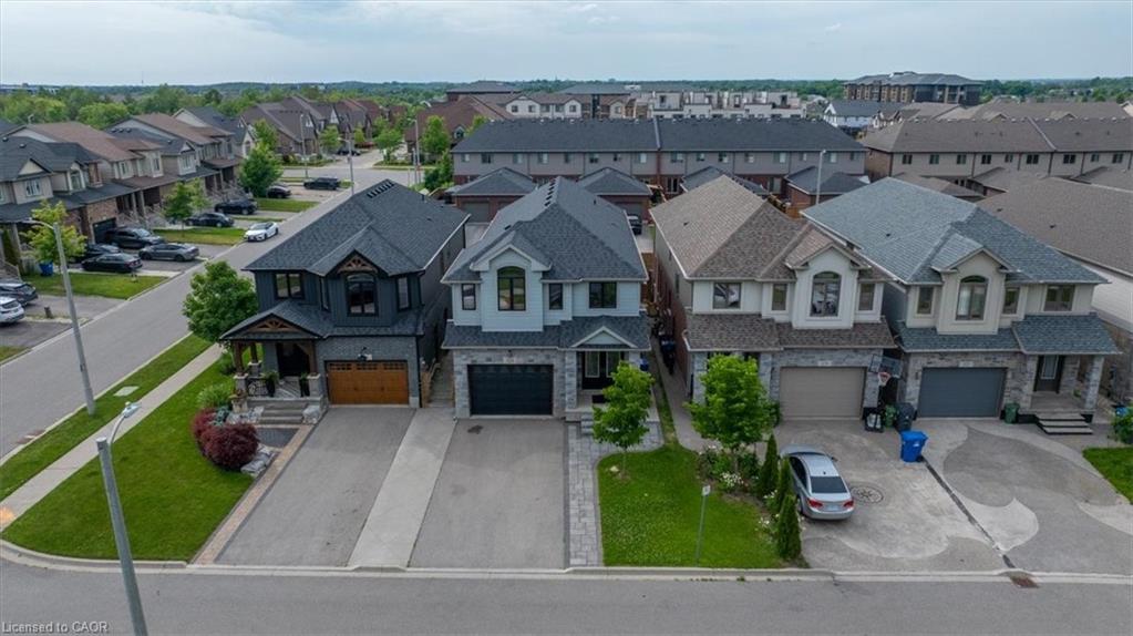 Contemporary two-story residence with a dark gray facade, stone accents, and a prominent wood-finish garage door