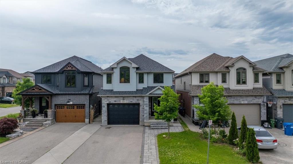 Contemporary two-story residence featuring a light blue exterior with stone accents and a dark roof