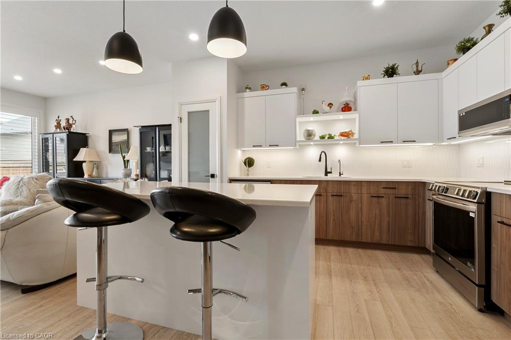 Contemporary kitchen featuring white upper cabinetry, wood-finish lower cabinetry, and light-toned wood-finish flooring