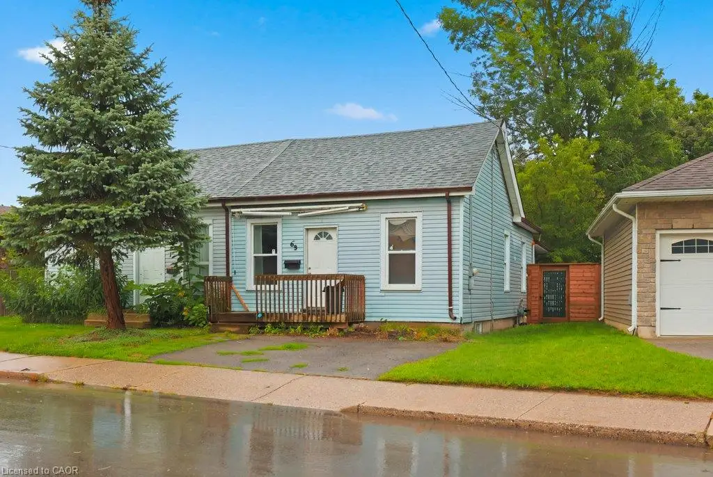 Light blue siding exterior with a dark gray shingle roof, front wooden porch, and a paved driveway