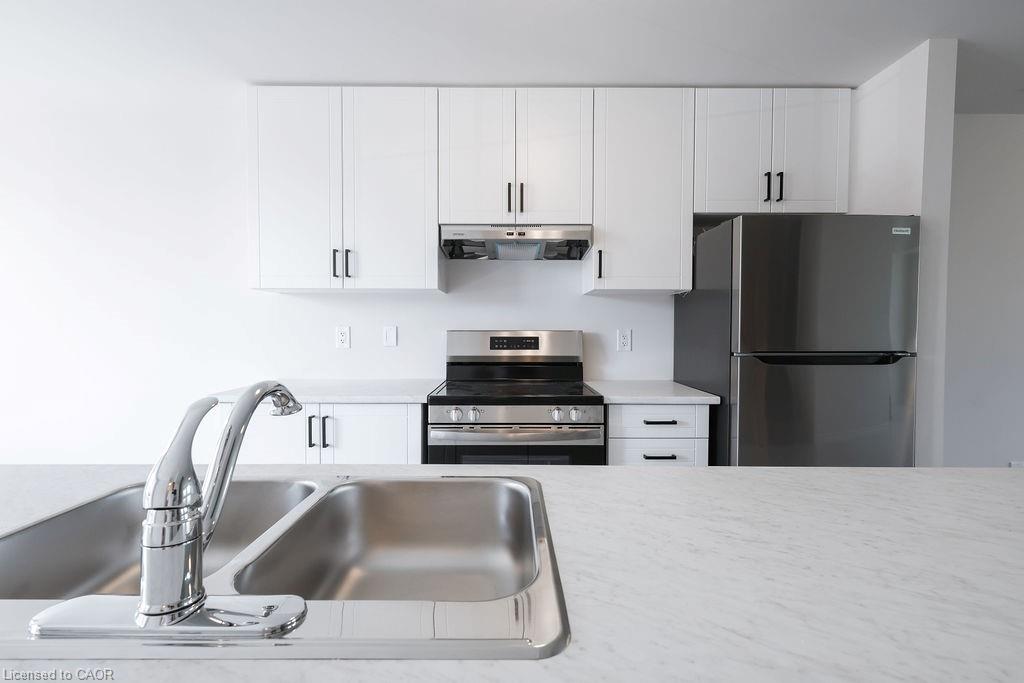 Kitchen featuring white upper and lower cabinetry with black hardware, stainless steel appliances, and a dual basin sink with chrome faucet