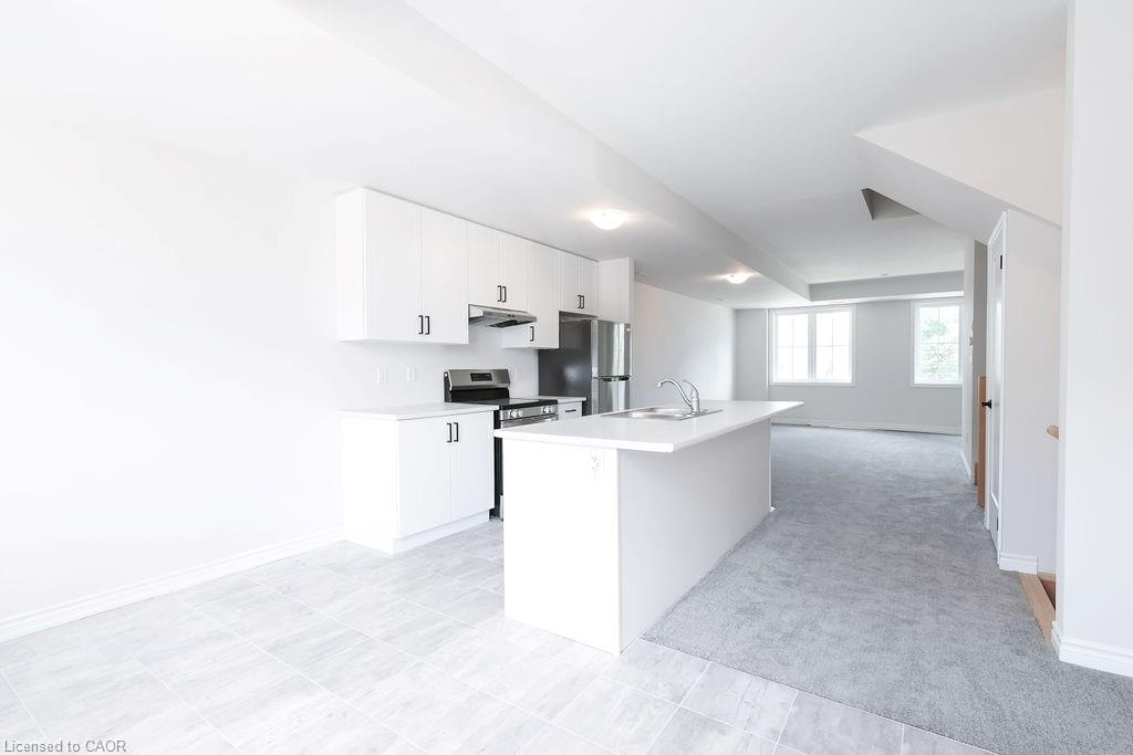 Contemporary kitchen featuring white cabinetry, stainless steel appliances, a center island with sink, and light gray tiled flooring