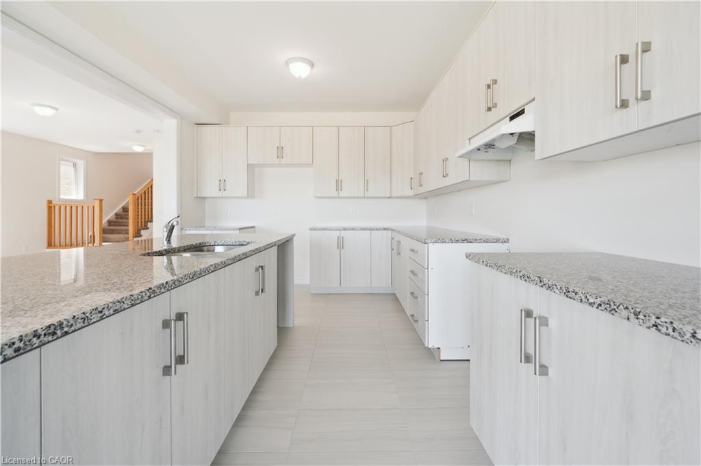 Kitchen featuring extensive cabinetry, quartz countertops, a built-in sink, and tile flooring