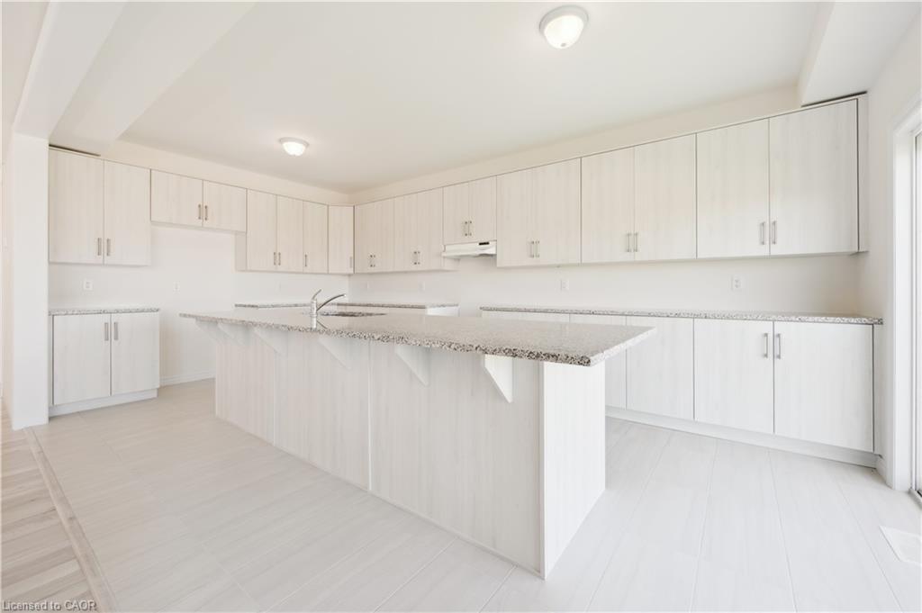 Spacious kitchen featuring an expansive 11 foot island, light wood-finish cabinetry, quartz countertops, and tile flooring