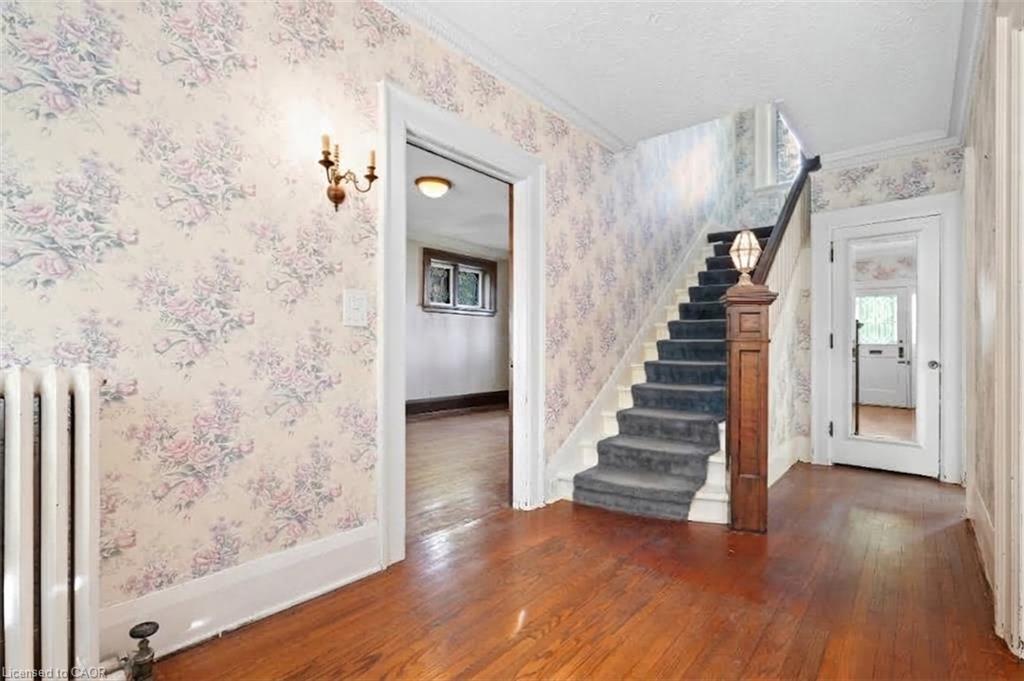 Wood-finish flooring with a carpeted staircase and ornate newel post
