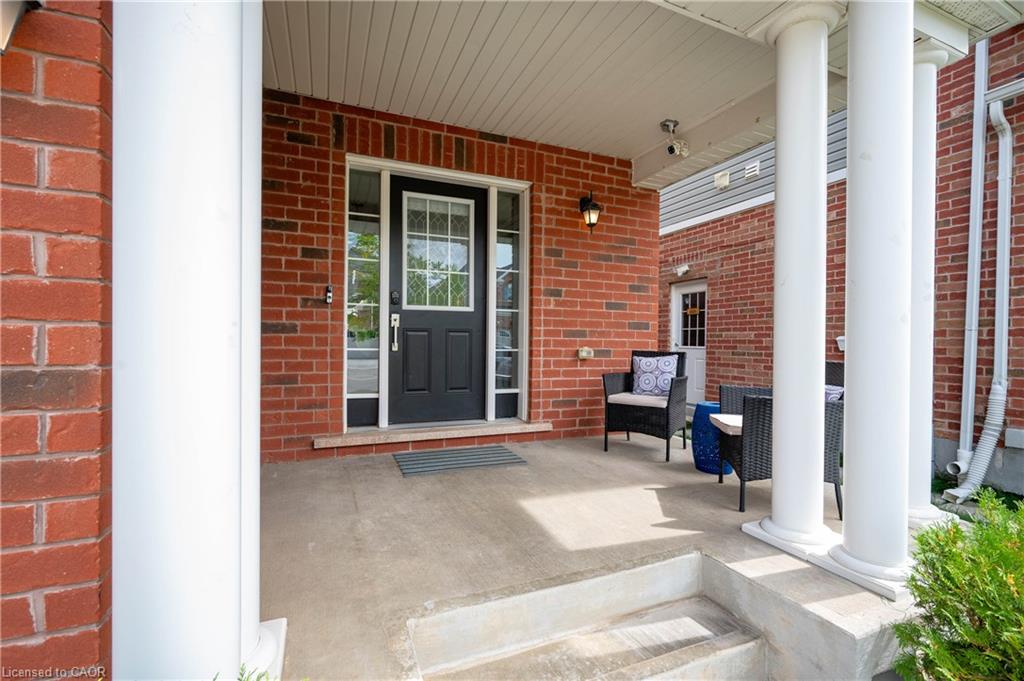Brick facade with a covered front porch, concrete steps, and white columns