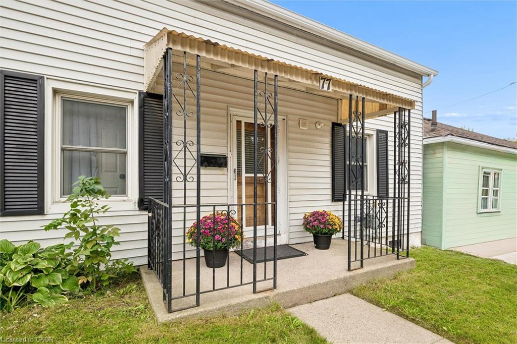 Front porch featuring a decorative awning, wrought iron railings, and a concrete walkway