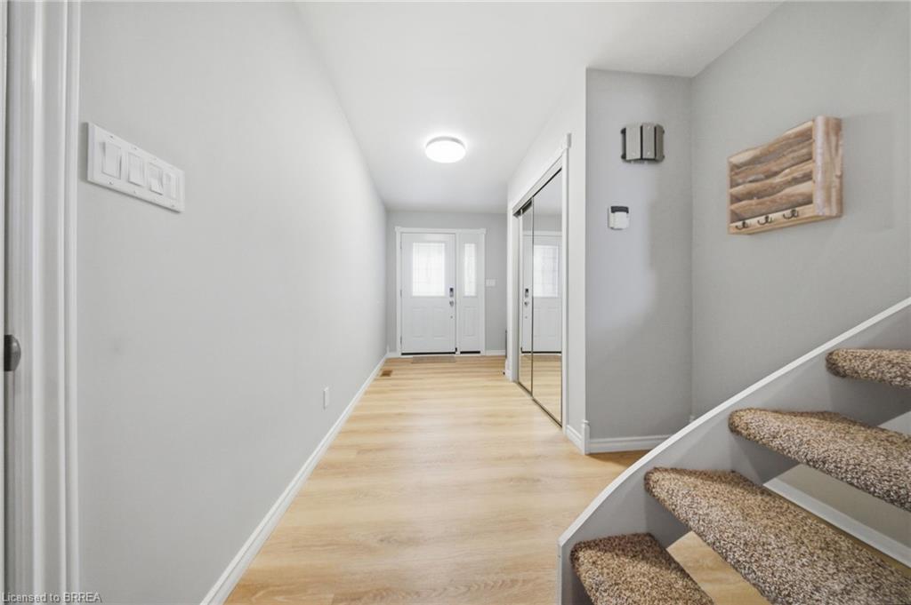 Entryway featuring light wood-style flooring, a white front door with an upper window pane, mirrored closet doors, and carpeted stairs