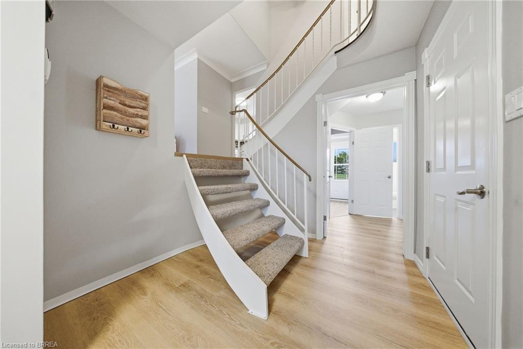 Welcoming entryway featuring light-toned flooring, a carpeted staircase with a white banister, and white paneled doors