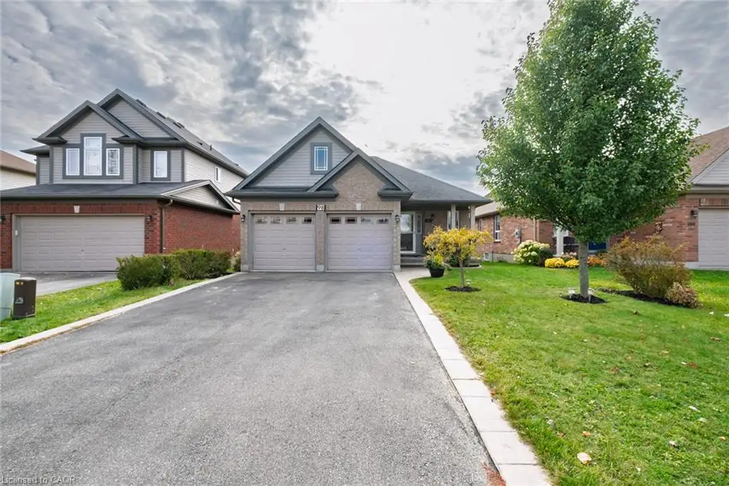 Exterior featuring a brick and horizontal siding façade, double-car garage with overhead doors, asphalt driveway, and landscaped front lawn
