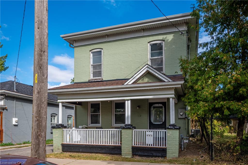 Two-story brick exterior with a covered front porch, white railing, and decorative trim