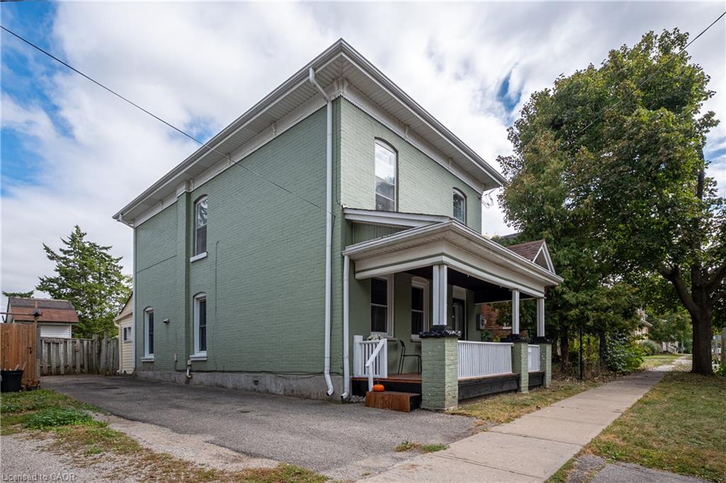 Two-story painted brick exterior with a covered front porch, white trim, and a paved driveway