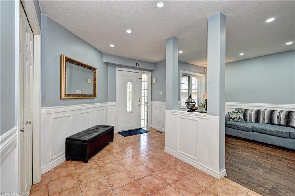 Entryway featuring ceramic tile flooring, wainscoting, recessed lighting, a white paneled door with decorative glass inserts, and a coat closet