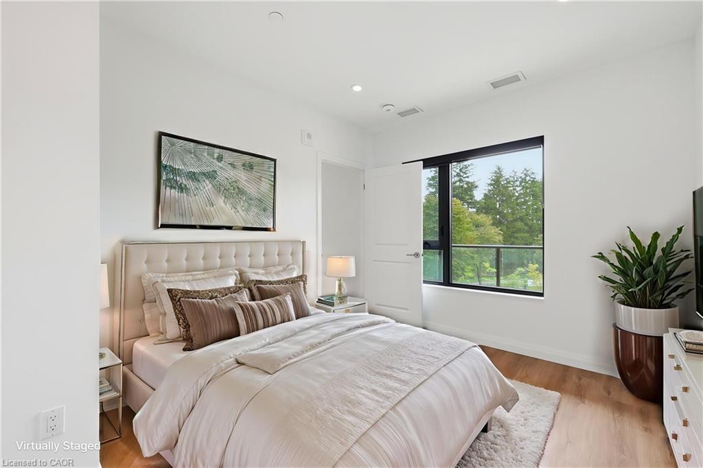 Spacious bedroom featuring light wood-finish flooring, a contemporary window, white walls, recessed lighting, and a neutral color palette