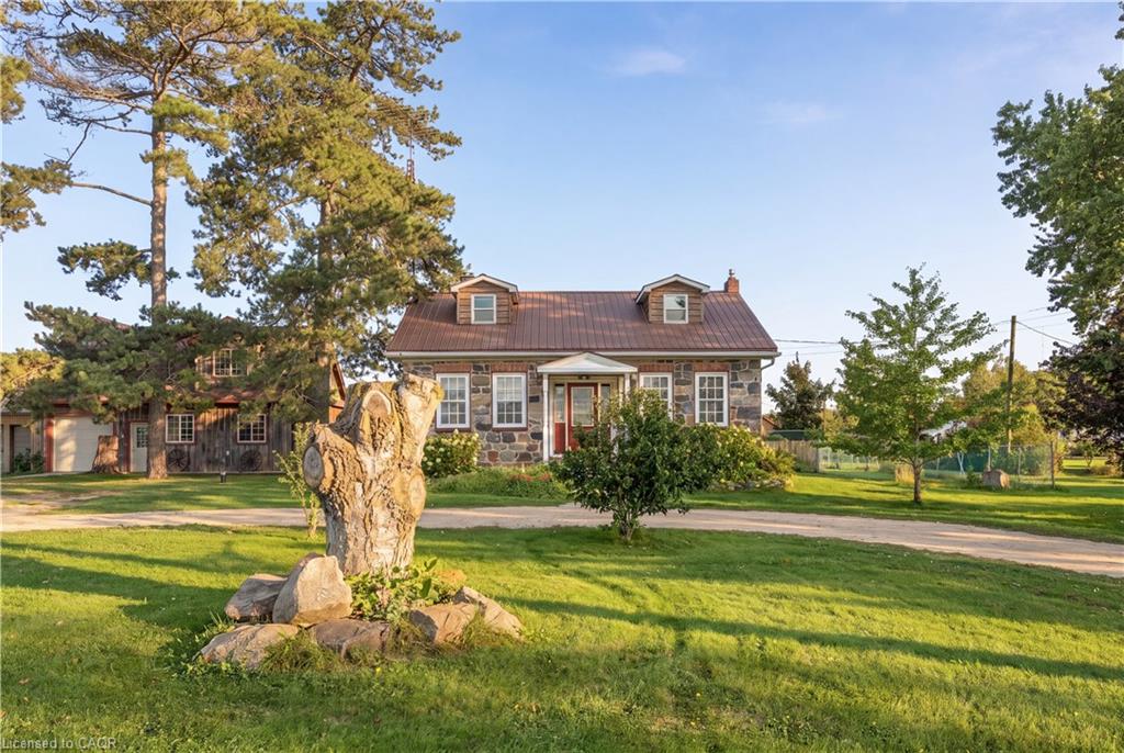 Stone exterior residence with a metal roof, dormer windows, and a covered front entry