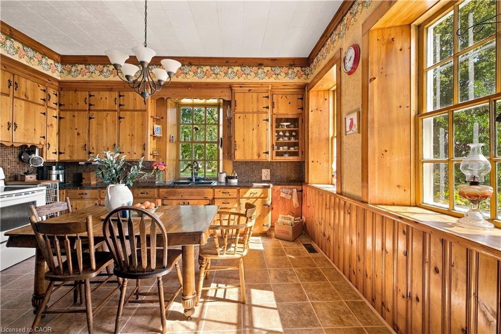 Wood-paneled walls and cabinetry, multiple windows with natural light, tiled flooring, and a built-in kitchen sink