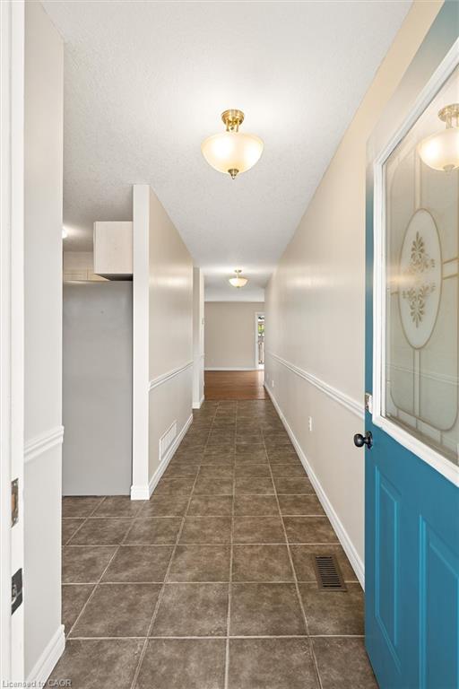 Tiled entry flooring with recessed lighting, crown molding, and a paneled door with decorative glass insert