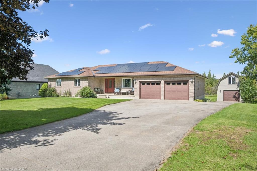Brick exterior with solar panels, a two-car attached garage, and a separate detached garage with an upper level