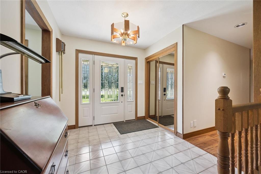 Entryway featuring white tile flooring, a double front door with decorative glass inserts, and wood-finish trim