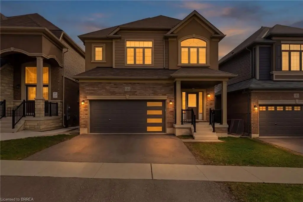 The property features a stone and siding exterior, an attached two-car garage with modern frosted glass panels, and a covered front porch