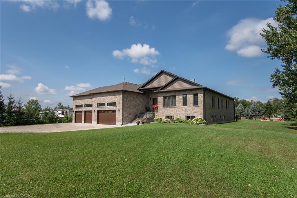 Brick exterior with a three-car garage, multiple windows, and a front porch entry