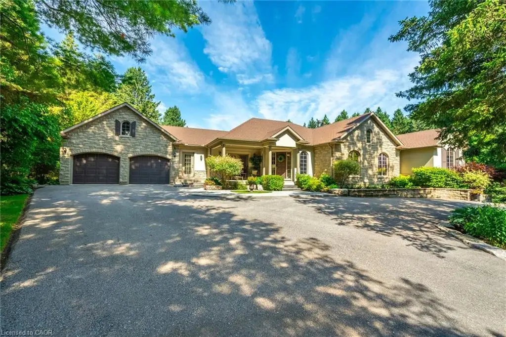 View of front of house with stone siding, aphalt driveway, and an attached garage