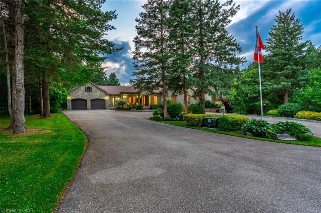 View of front of house featuring stone siding, an attached garage, aphalt driveway, and a front yard