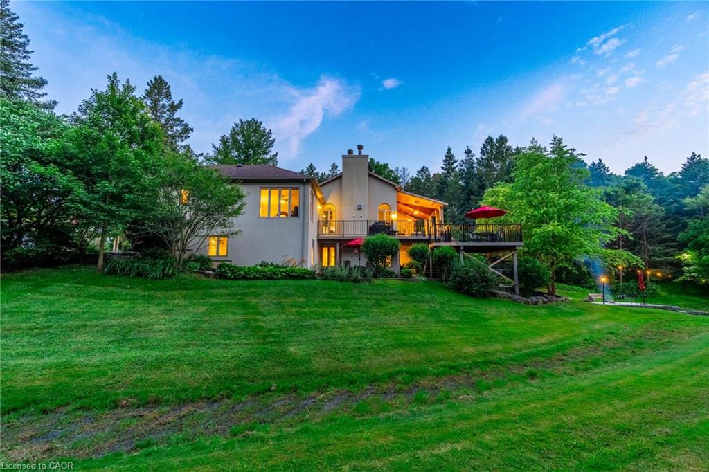 Rear view of property featuring stucco siding, a chimney, a lawn, and a deck