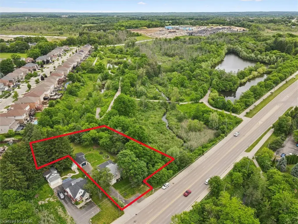 Aerial perspective of a property lot featuring mature trees, a detached garage, and direct frontage to a public thoroughfare