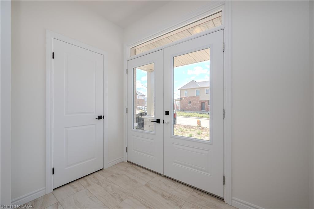 Double entry doors with transom window, tile flooring, and matte black hardware