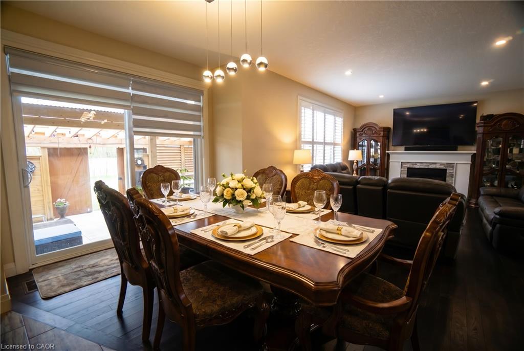 Open-concept dining and living area featuring dark wood-finish flooring, recessed lighting, and a contemporary linear pendant light fixture