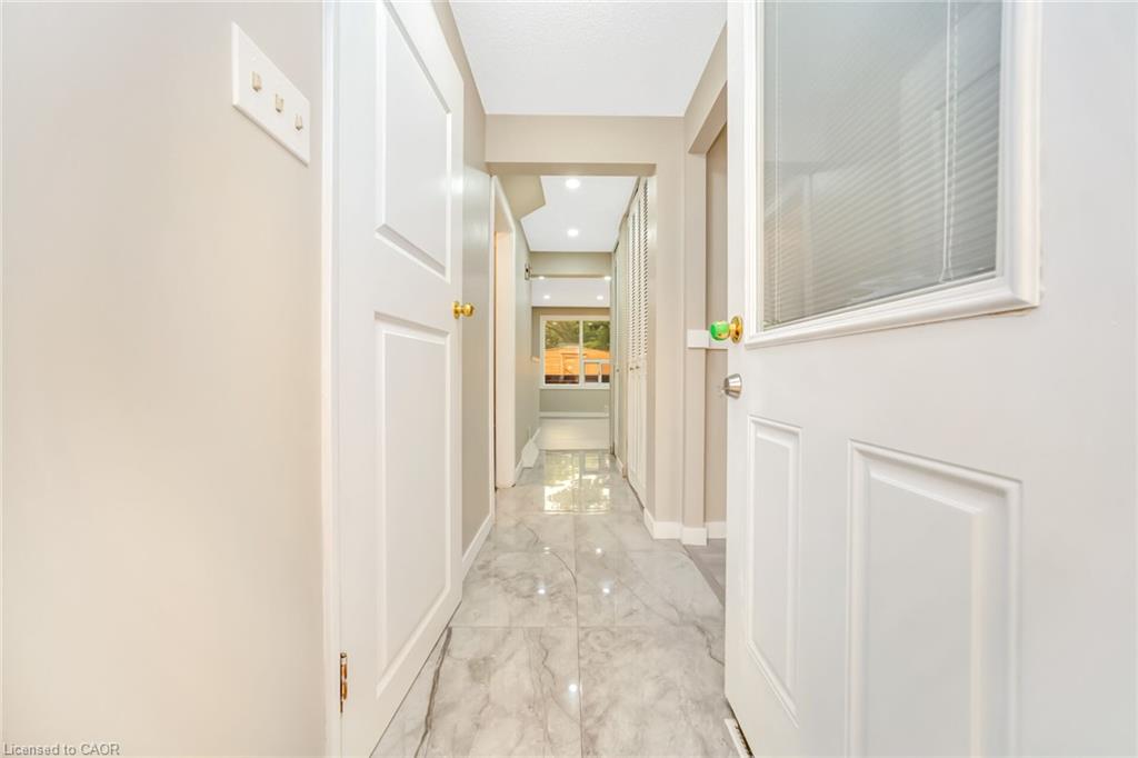 Hallway featuring polished tile flooring, recessed lighting, white paneled doors, and a partial glass door with integrated blinds