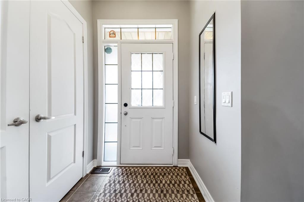 Entryway featuring a white paneled door with grid-patterned glass, a sidelight, and an overhead transom window