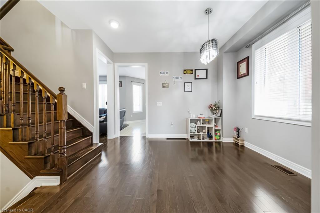 Spacious interior featuring dark wood-finish flooring, a grand staircase with dark wood newel posts and balusters, and light gray wall paint