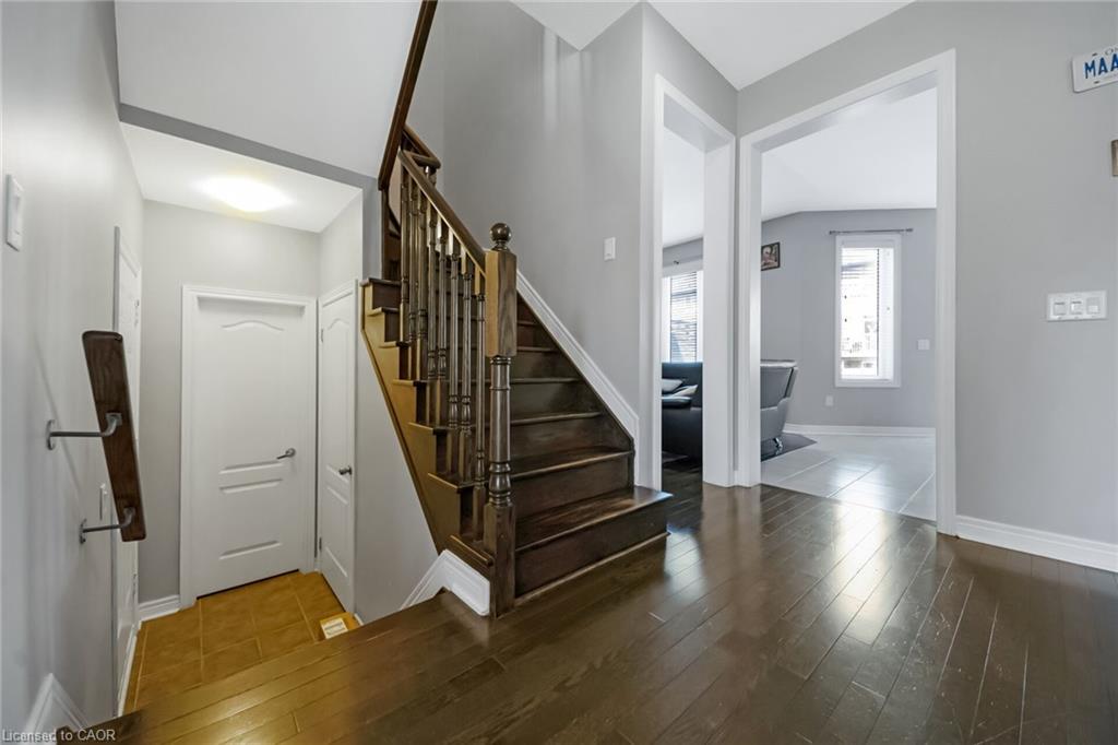 Entryway featuring dark wood-finish flooring, a coordinating wooden staircase with balusters, and a light gray wall color