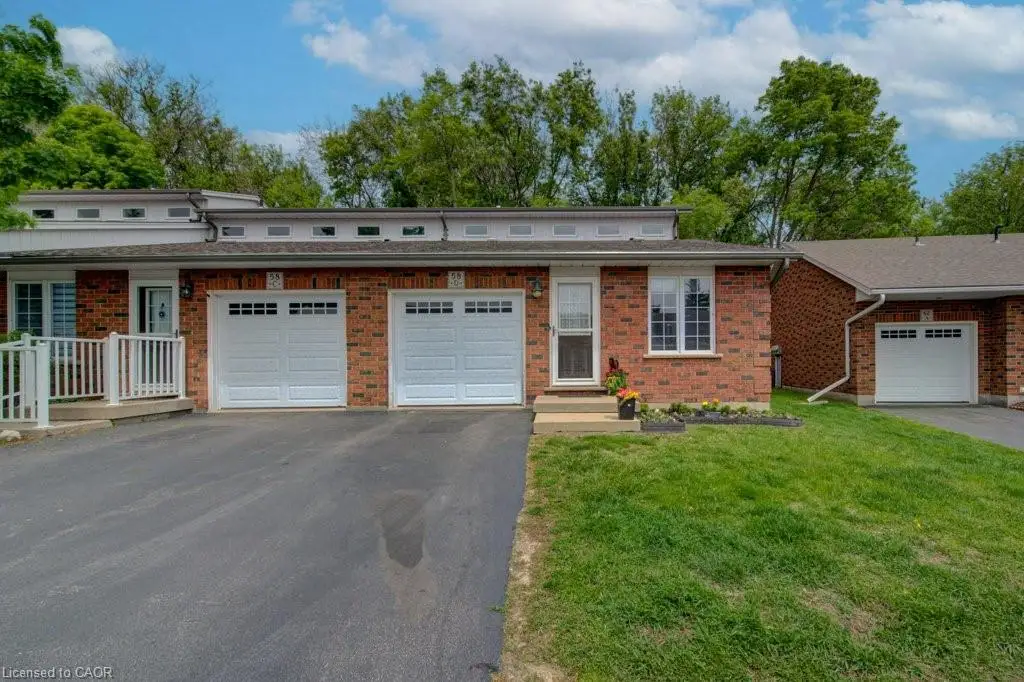 Brick exterior architecture featuring a two-car garage, white frame windows, and a landscaped front garden bed