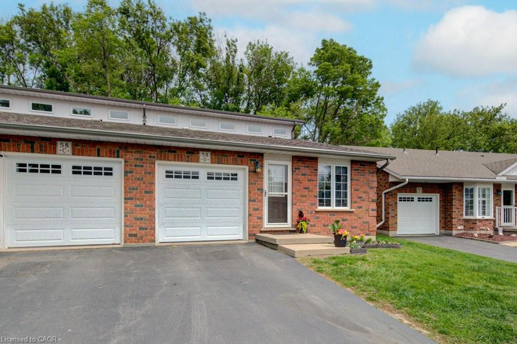 Brick exterior featuring multiple garages with panel doors and window inserts, an asphalt driveway, and a front entrance with a storm door