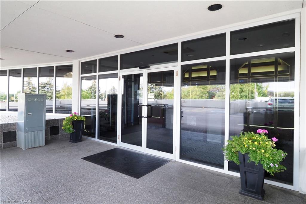 Modern building entrance featuring a glass storefront with automatic double doors, recessed lighting, and a granite-look tiled walkway