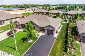 Ranch-style residence featuring a stone and siding facade, an attached garage, a paved driveway, and a front lawn with established trees