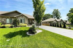 Stone and siding exterior with a prominent front lawn, established landscaping, and a paved driveway