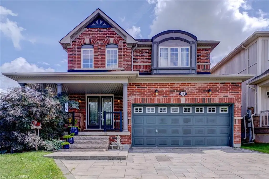 Brick exterior with a covered porch, an attached garage, a dormer window, and a paver driveway
