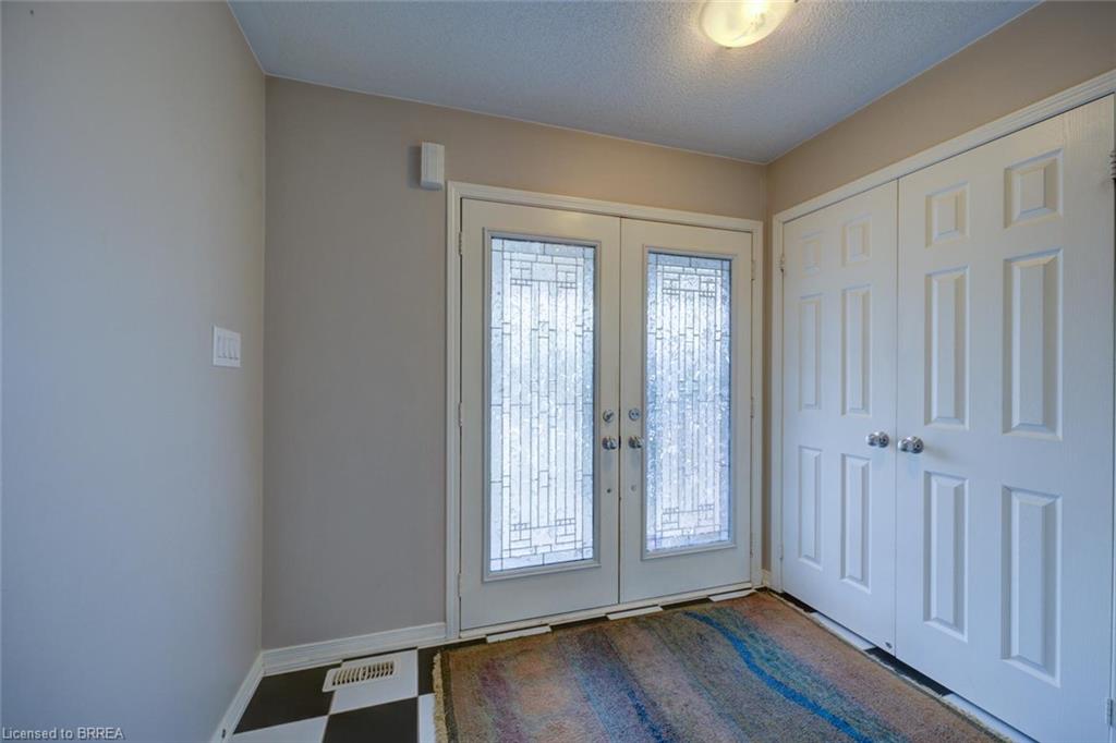 Double entry doors with decorative glass panels, checkered flooring, and a flush mount ceiling light