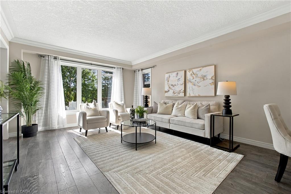 Spacious living area featuring wood-finish flooring, a large bay window, and crown molding