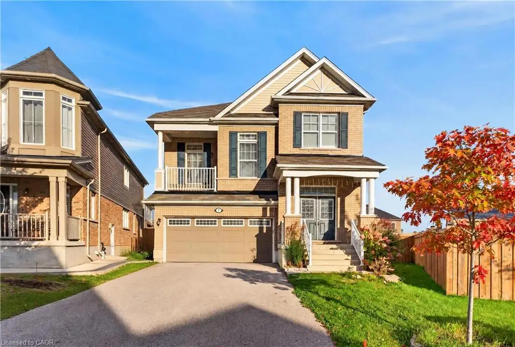 Two-story brick and siding exterior featuring an integrated two-car garage, second-level balcony, covered front entryway with decorative columns, and asphalt-shingle roof