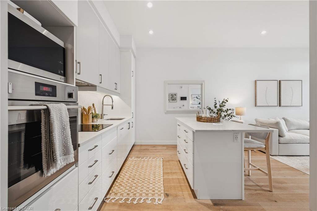 Modern kitchen featuring white cabinetry, integrated stainless steel appliances, a center island, recessed lighting, and wood-finish flooring