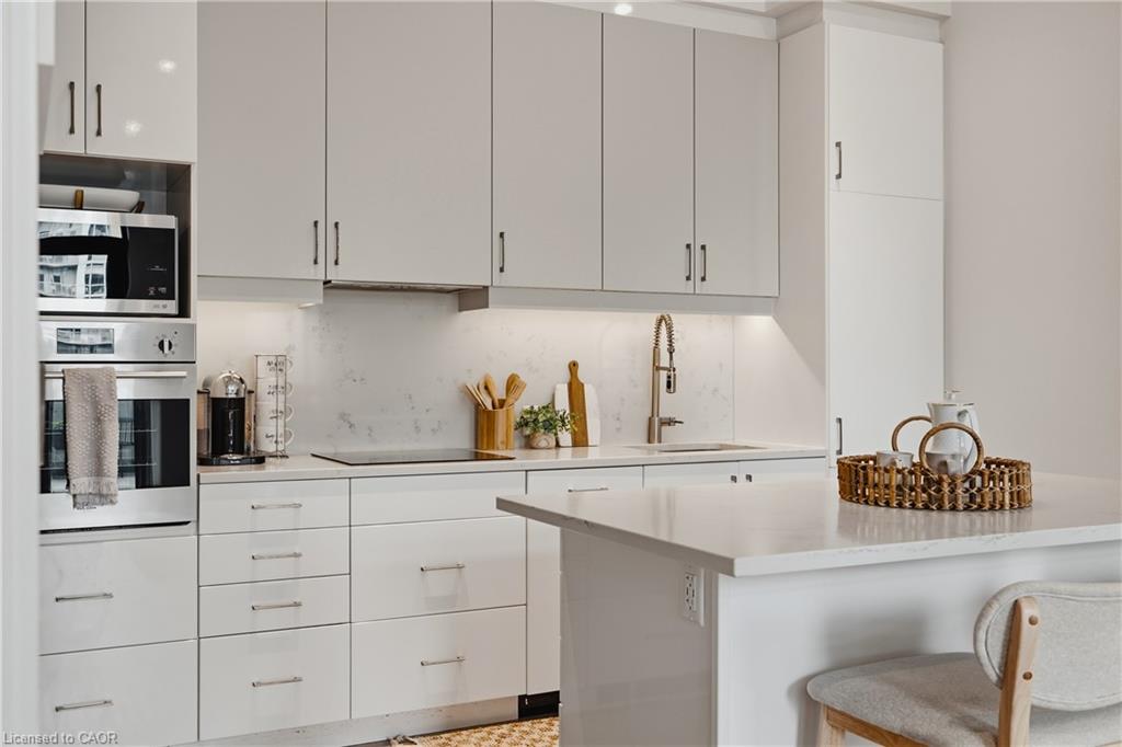 Sleek kitchen featuring light-toned cabinetry, integrated stainless steel appliances, a built-in oven, and a contemporary sink with a gooseneck faucet